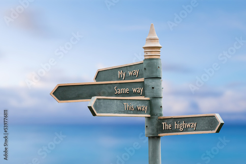 my way same way this way the highway quote written on fancy steel signpost outdoors by the sea. Soft Blue ocean bokeh background.