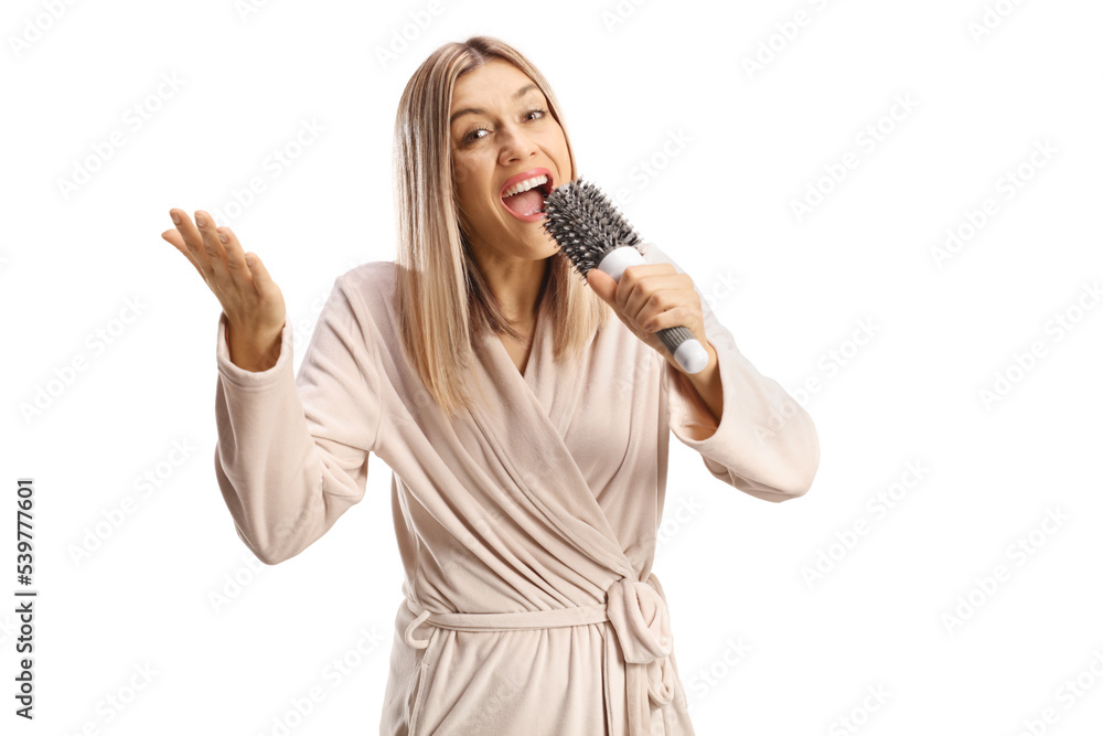 Cheerful young woman in a bathrobe singing and holding a hair brush Cheerful young woman in a bathrobe singing and holding a hair brush
