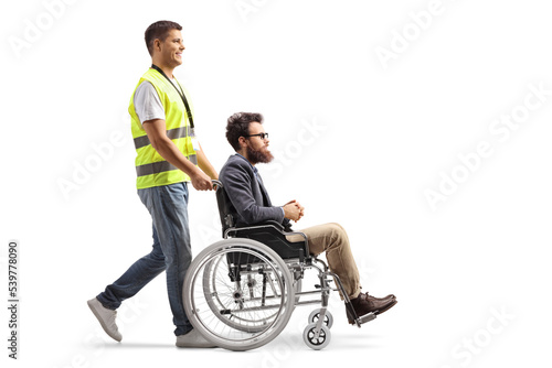 Full length profile shot of a community worker pushing a man in a wheelchair