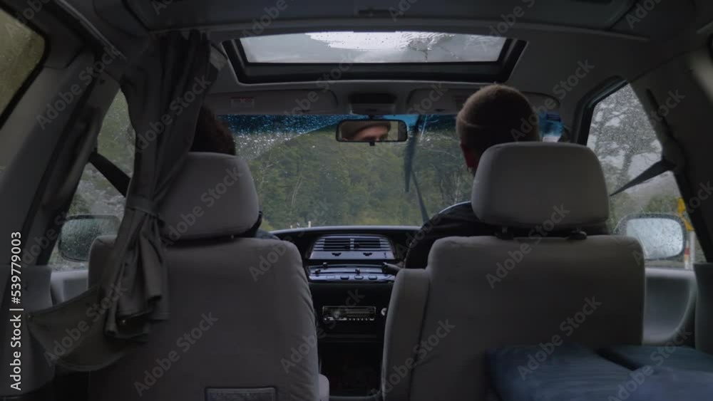 A couple drives a campervan in the rain, in New Zealand A couple drives a campervan in the rain, in New Zealand