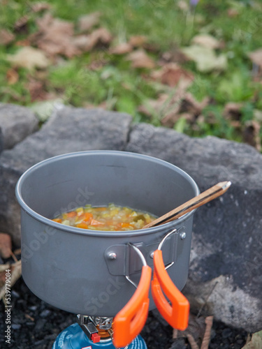 Outdoor winter meal concept pot of vegetable soup on outdoor camping gas stove.