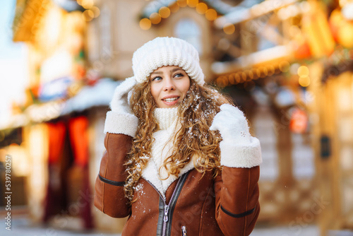 Beautiful woman in winter style clothes posing in Christmas market decorated with holiday lights. Holidays, rest, travel concept.