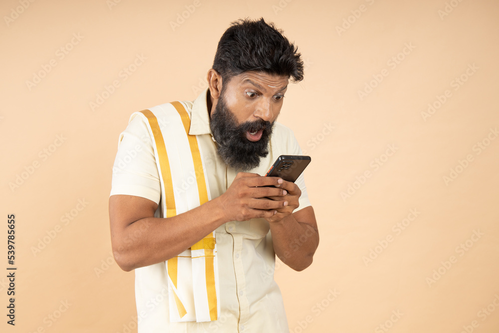 Amazed or shocked South indian man with open mouth using mobile phone ...