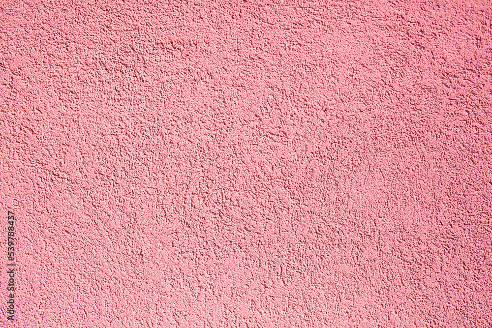 Fototapeta premium Background of pink concrete wall. Decorative embossed concrete and glue plaster. Pink plastered wall. Plaster textured background. Blurred photo