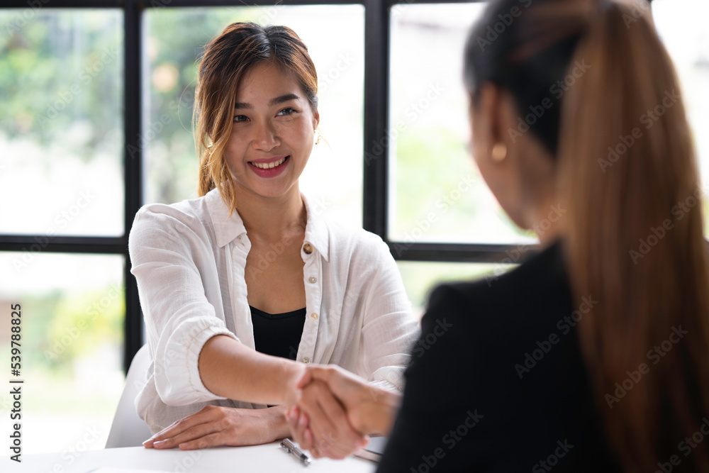 Attractive Asian business women shake hands after successful business deal, consensus business meeting. Attractive Asian business women shake hands after successful business deal, consensus business meeting.