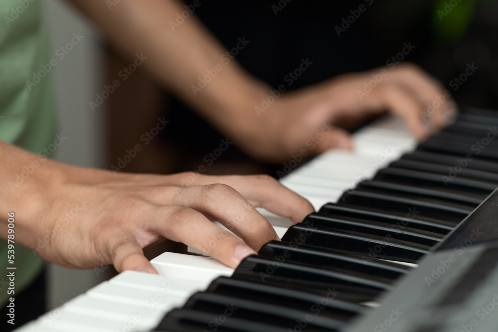 Teenager's hands on the keys of an electronic piano instrument, selective focus, the concept of music school classes