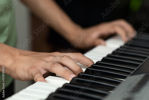 Teenager's hands on the keys of an electronic piano instrument, selective focus, the concept of music school classes
