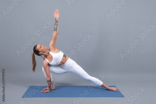 Fitness woman. Beautiful young girl in sportswear doing stretching for legs. Sports clothing, sportswear. Young beautiful model on training near gray background.
