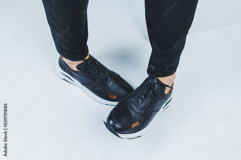 Men's legs in casual shoes of black color made of genuine leather, men on shoes in black sneakers. High quality photo Men's legs in casual shoes of black color made of genuine leather, men on shoes in black sneakers. High quality photo