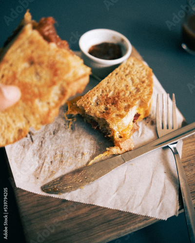 A focaccia bread salami toastie served with pickle, salad and a coffee in a cafe environment. photo