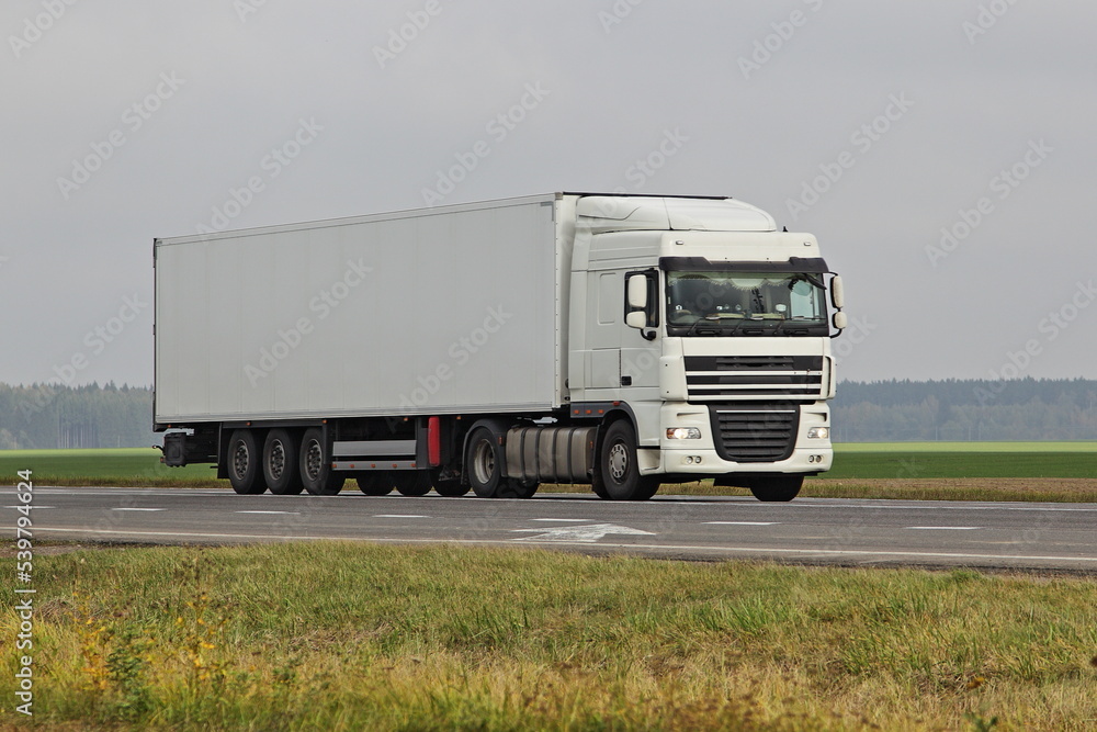 White semi truck drive on countryside highway road on green field . Front side view . International transportation logistics