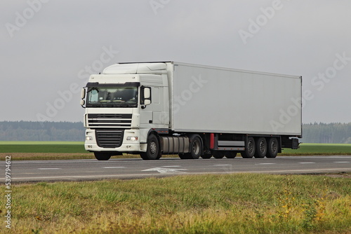 White semi truck drive on countryside highway road on green field at autumn day. Front side view . Long hauls ransportation logistics