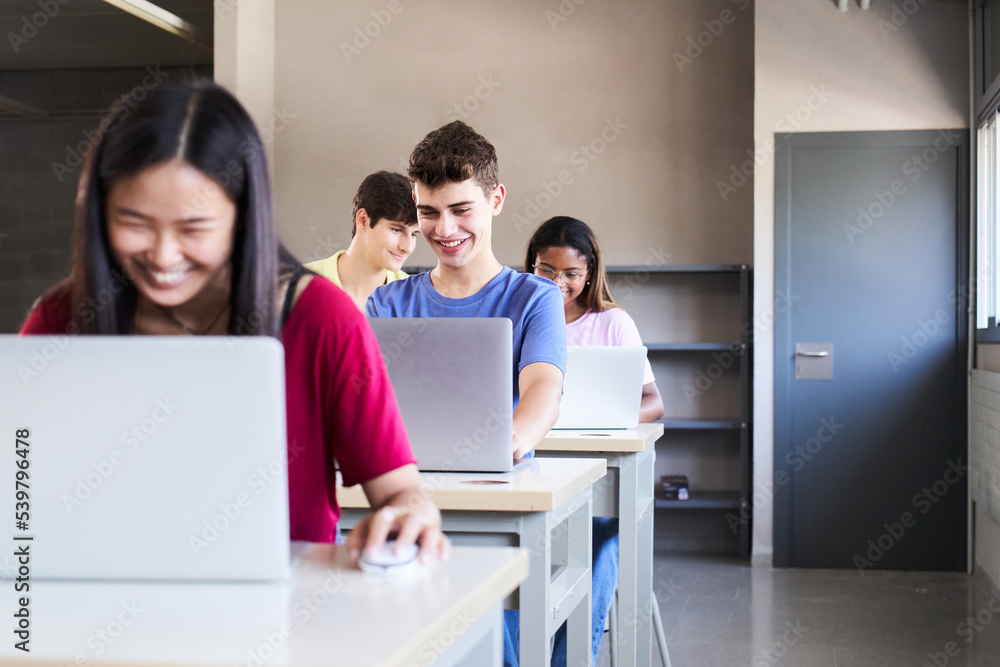Large Group of Multi Ethnic smiling Students Working on the Laptops while Listening to Lecture in the Classroom. Young cheerful People Study University. Selective focus in the guy. High quality photo Large Group of Multi Ethnic smiling Students Working on the Laptops while Listening to Lecture in the Classroom. Young cheerful People Study University. Selective focus in the guy. High quality photo