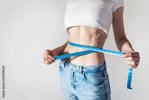 Woman checking waistline with blue measuring tape