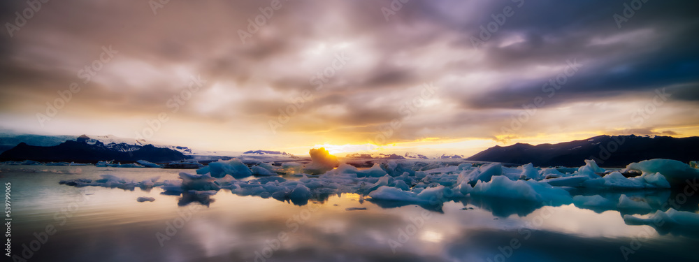 Beautiful colorful sunset sets over iceberg with colorful sky in this winter  scene from Iceland with cloudy sky water reflection illustrating global warming  