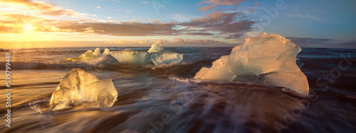 Bright sunshine over icy winter iceberg filled ocean in Iceland with cold sea water and floating glacier  