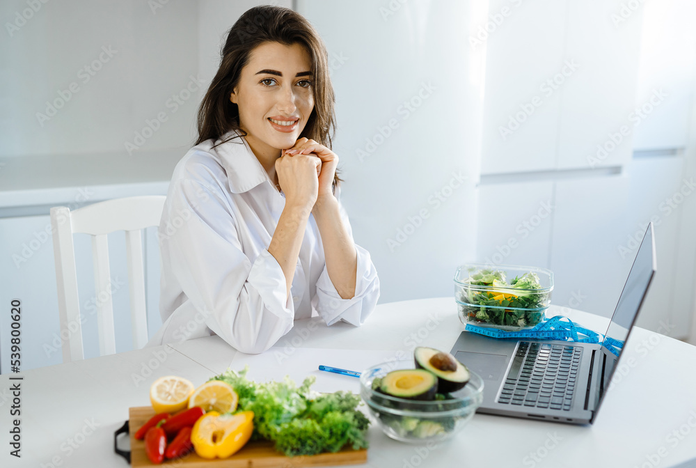 Dietitian, nutritionist, healthy diet expert sitting at desk with raw vegetables sharing health advice on medical vlog or video calling patient and giving online consultation Dietitian, nutritionist, healthy diet expert sitting at desk with raw vegetables sharing health advice on medical vlog or video calling patient and giving online consultation