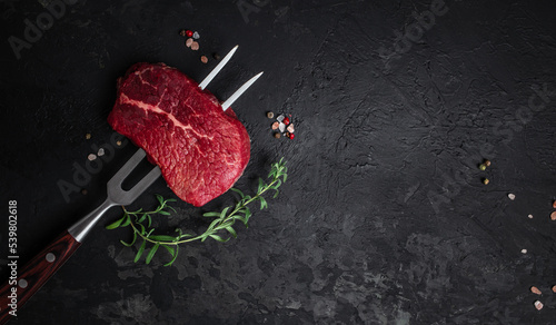 raw beef steak on a fork with rosemary and spices. Preparing fresh beef steak, Long banner format. top view