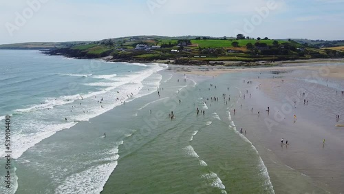 Many people spend their leisure time on the Irish beach of Inchydoney, top view. Beautiful Irish coast in summer, drone video. Seascape and a huge sandy beach.