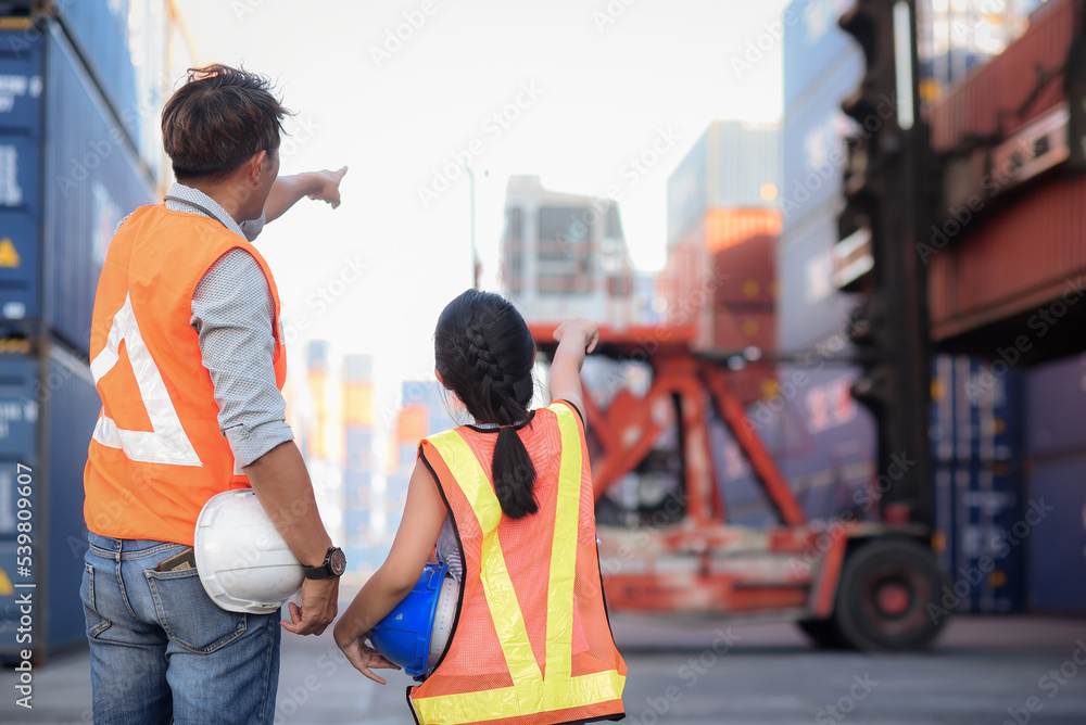 Back side of Asian father who owns an import-export and warehouse business. looking and pointing at containers and introducing and educate her knowledge of work for a daughter who wants to learning Back side of Asian father who owns an import-export and warehouse business. looking and pointing at containers and introducing and educate her knowledge of work for a daughter who wants to learning