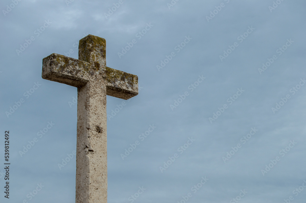 A lone stone cross silhouetted against a sky