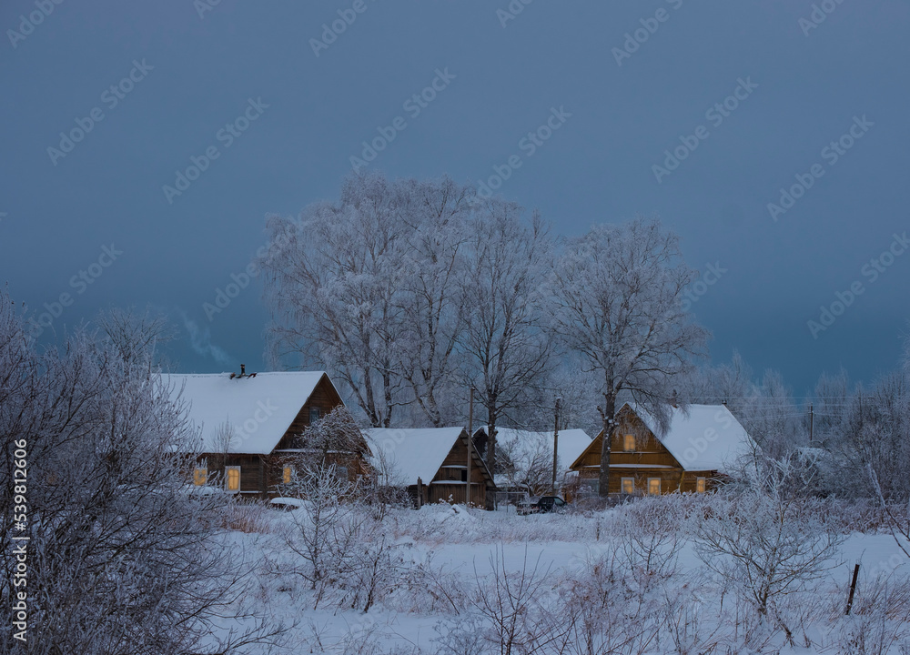 Small cozy village with wooden houses in snow, beautiful winter evening