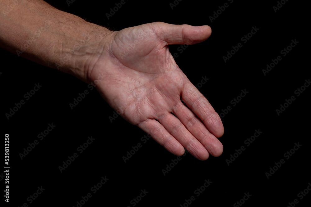 The outstretched greeting hand of an elderly man, isolated on a black background. The outstretched greeting hand of an elderly man, isolated on a black background.