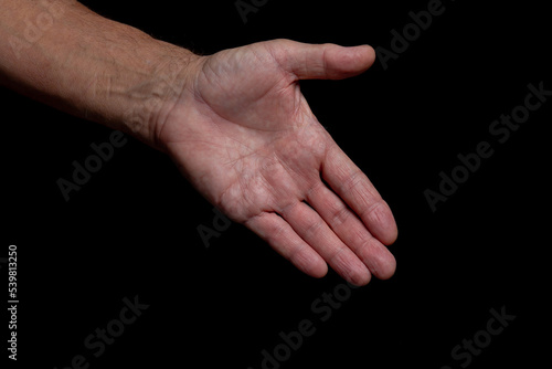 The outstretched greeting hand of an elderly man, isolated on a black background. 