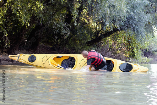 Tablou pe pânză Kayaker turning over (capsize) in river near shore