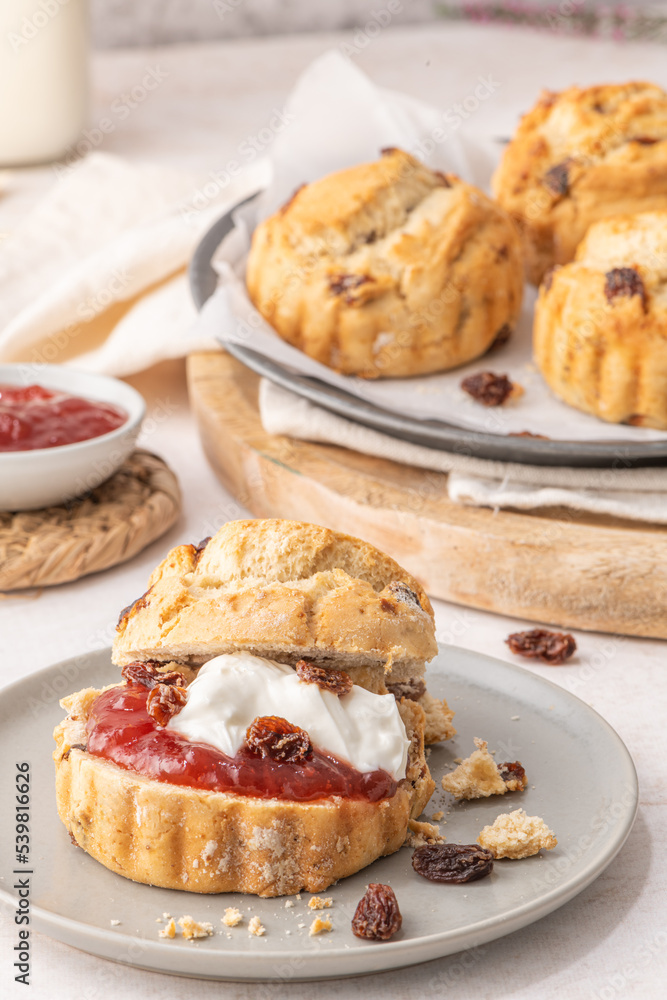 Homemade raisin scones with clotted cream and strawberry jam ready to eat Homemade raisin scones with clotted cream and strawberry jam ready to eat