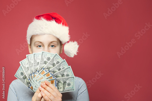 Earnday. US dollars in teen in Santa hat  hands photo