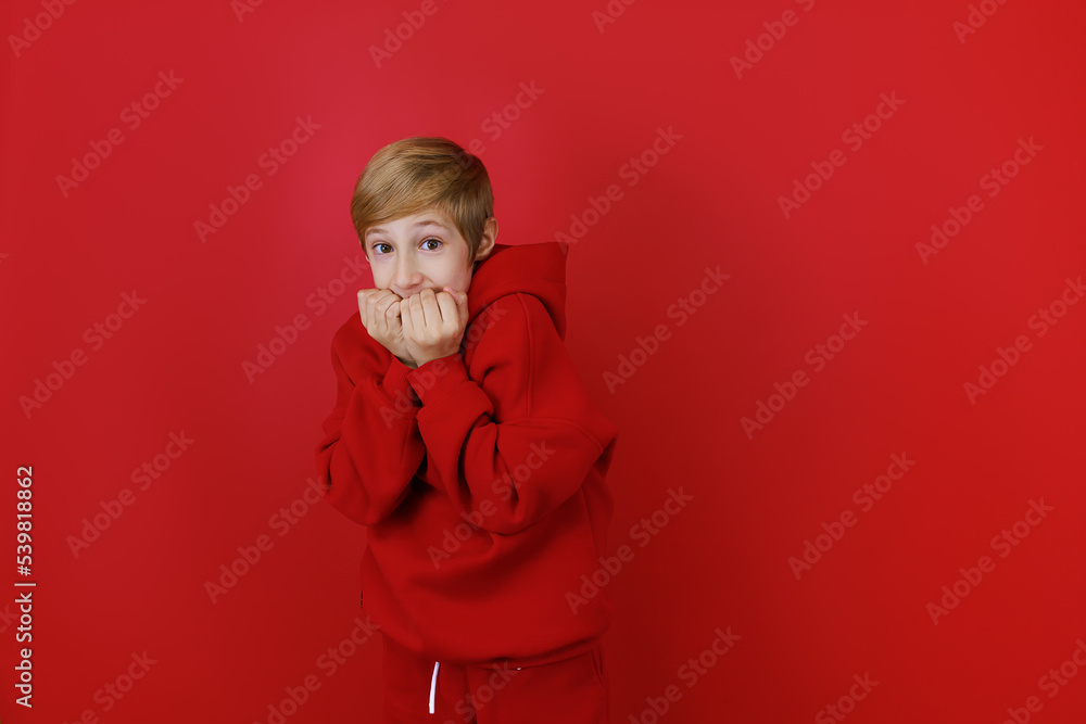 a boy in a red tracksuit got scared and bites his nails from fright a boy in a red tracksuit got scared and bites his nails from fright