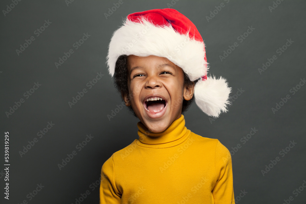 Laughing kid in Santa hat on gray background Laughing kid in Santa hat on gray background
