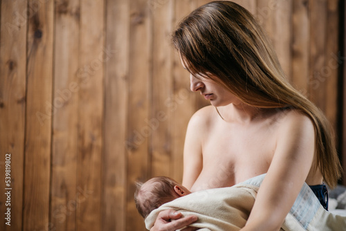 Mom with a newborn baby in a warm environment with a wooden background  pastel colors. Love and tenderness. High quality photo