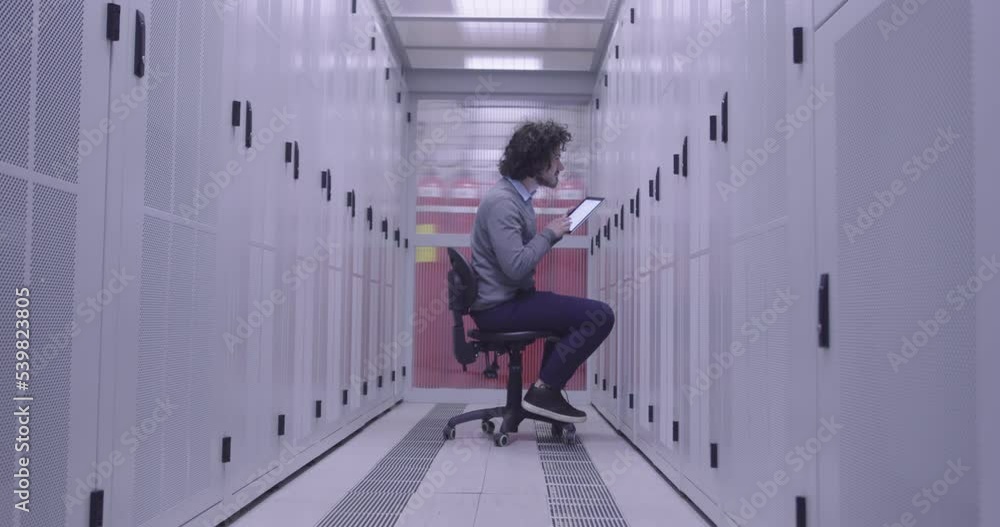 IT engineer or data science specialist working on tablet computer in server room at a modern cloud computing virtual data center supercomputer. IT engineer or data science specialist working on tablet computer in server room at a modern cloud computing virtual data center supercomputer.