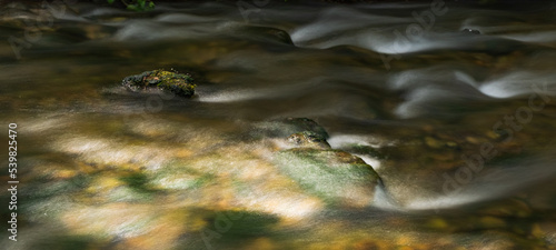 Long exposure with a rock in the colorful riverbed with water flowing 1