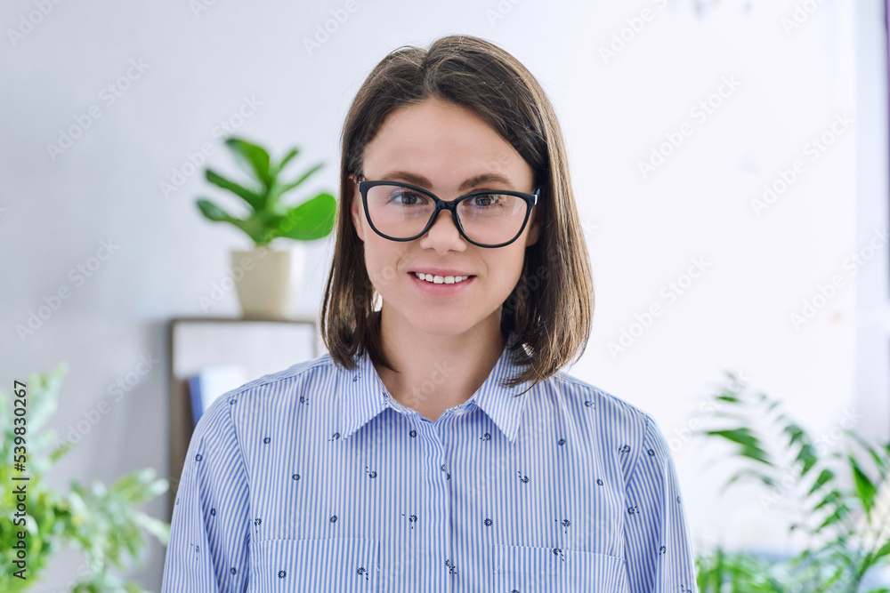 Headshot young smiling woman looking at camera in home interior Headshot young smiling woman looking at camera in home interior