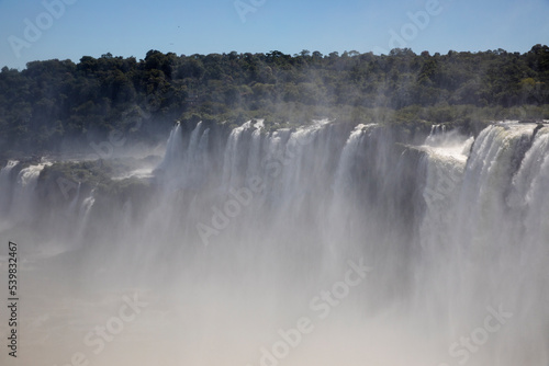 Natural world wonder. View of the Iguazu falls seen from Garganta del Diablo, in the frontier between Argentina and Brazil. The waterfalls falling white water texture and mist in the tropical forest.