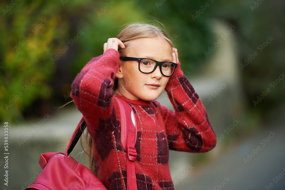 Outdoor portrait of adorable little girl walking to school, wering backpack and glasses Outdoor portrait of adorable little girl walking to school, wering backpack and glasses