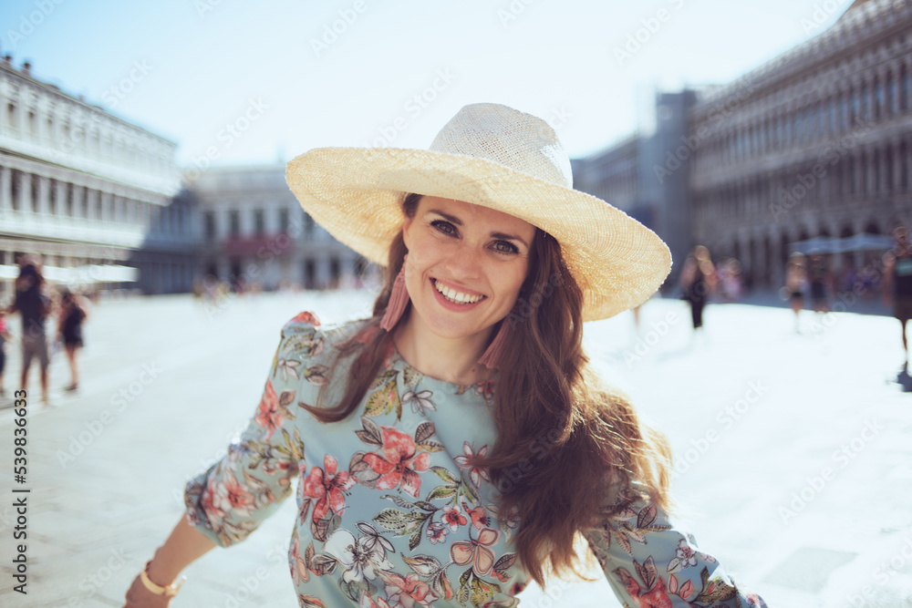 happy young woman in floral dress with hat having walking tour
