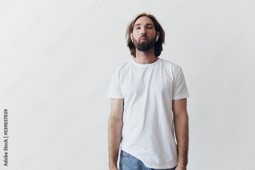 Stylish man in a white t-shirt with wireless headphones in his ears having fun listening to music smile on a white background lifestyle Stylish man in a white t-shirt with wireless headphones in his ears having fun listening to music smile on a white background lifestyle