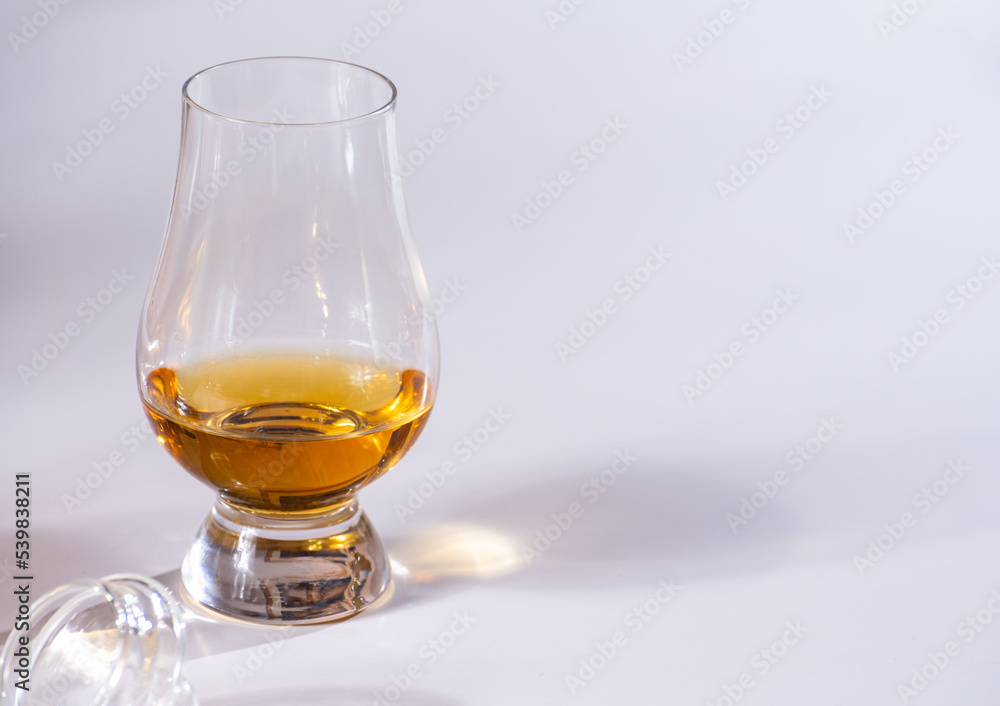 Tulip-shaped tasting glass with dram of Scotch single malt or blended whisky on white background Tulip-shaped tasting glass with dram of Scotch single malt or blended whisky on white background
