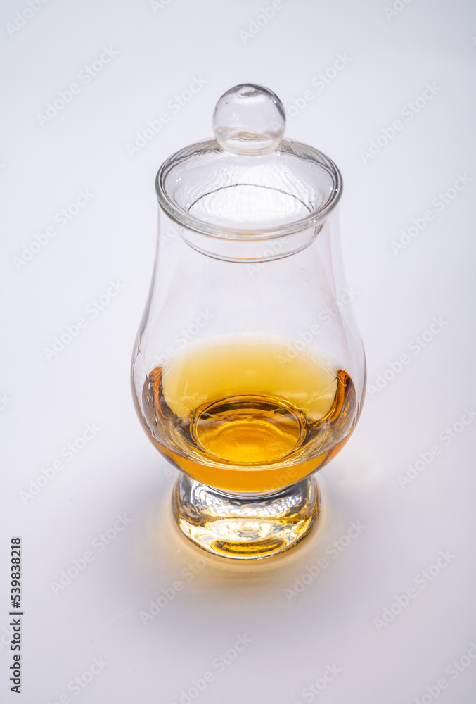 Tulip-shaped tasting glass with dram of Scotch single malt or blended whisky on white background Tulip-shaped tasting glass with dram of Scotch single malt or blended whisky on white background