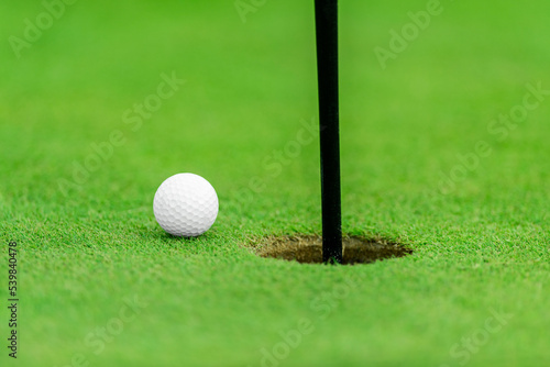 Flag, ball and hole at the beautiful golf course. Horizontal sport theme poster, greeting cards, headers, website and app.