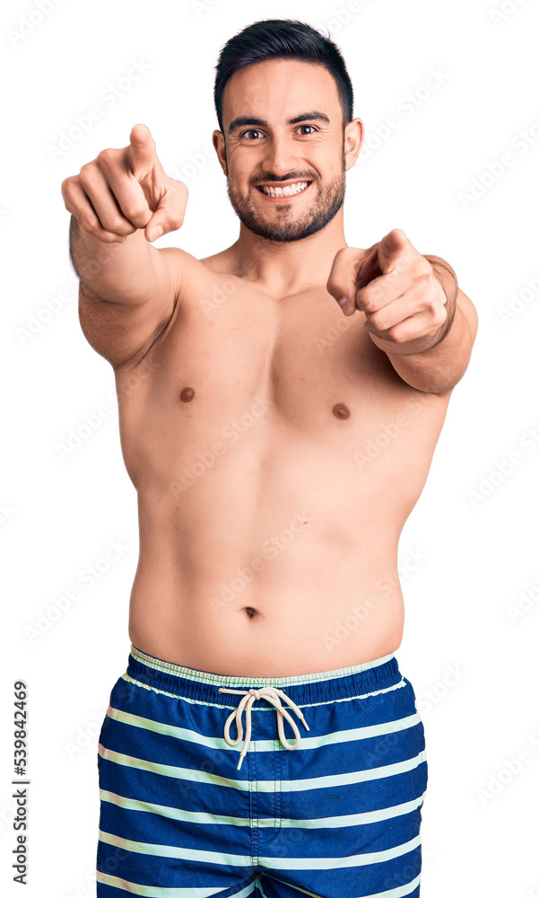 Young handsome man wearing swimwear pointing to you and the camera with fingers, smiling positive and cheerful Young handsome man wearing swimwear pointing to you and the camera with fingers, smiling positive and cheerful