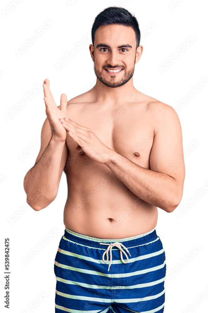 Young handsome man wearing swimwear clapping and applauding happy and joyful, smiling proud hands together Young handsome man wearing swimwear clapping and applauding happy and joyful, smiling proud hands together