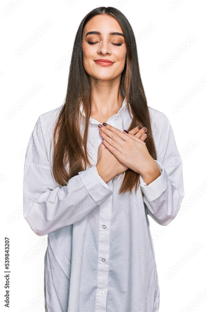 Young beautiful woman wearing casual white shirt smiling with hands on chest with closed eyes and grateful gesture on face. health concept.