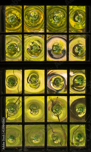 Detail of an old window made of crown glass or rondel window panes with warm autumn plants in the garden outside