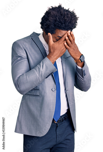 Handsome african american man with afro hair wearing business jacket with sad expression covering face with hands while crying. depression concept.