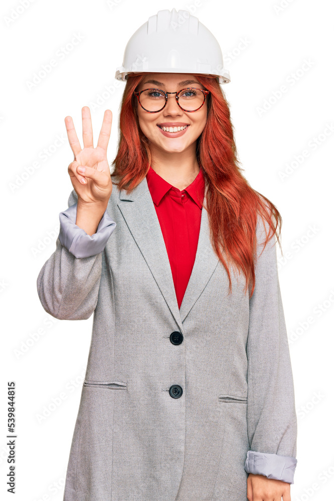 Young redhead woman wearing architect hardhat showing and pointing up with fingers number three while smiling confident and happy. Young redhead woman wearing architect hardhat showing and pointing up with fingers number three while smiling confident and happy.
